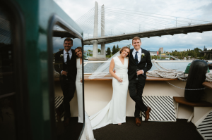 Willamette Star | Bow | Bride & Groom Wedding couple on bow of Willamette Star shown in reflection in the window with Tillikum Bridge in background