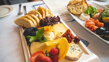 A beautifully arranged platter of cheese, fruit and dried fruits on display.